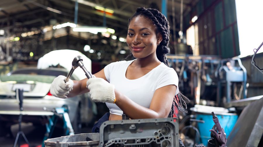 Young African woman working on aircraft components in an industrial workshop.